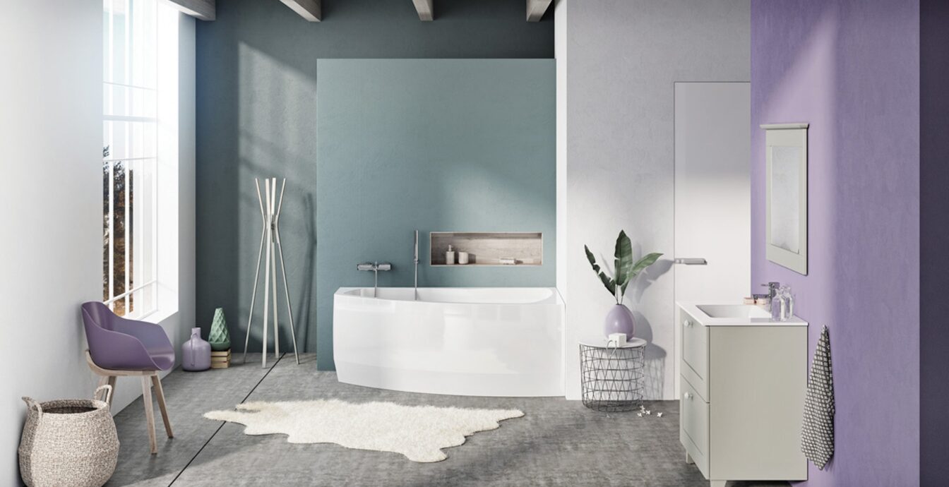 Heledas ja modernses vannitoas on valge Rhea akrüülvann, mille kõrval paiknevad valamu, peegel, lillakas sein ja suured aknad.